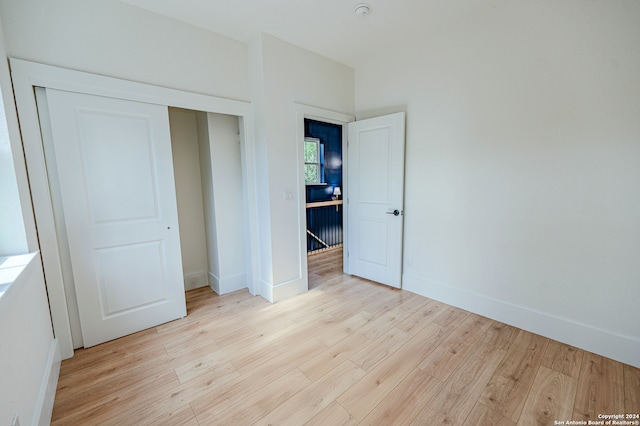 unfurnished bedroom with light hardwood / wood-style flooring and a closet