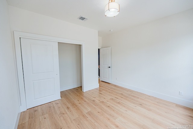 unfurnished bedroom with a closet and light wood-type flooring