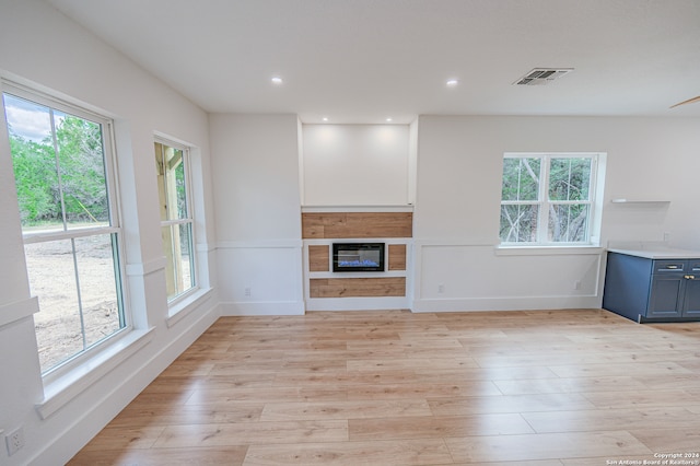 unfurnished living room with light wood-type flooring and a healthy amount of sunlight