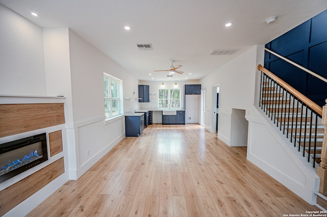 unfurnished living room featuring a textured ceiling, ceiling fan, and light hardwood / wood-style flooring