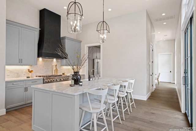 706 W Creek, Fredericksburg, TX 78624 - kitchen featuring gray cabinetry, exhaust hood, light stone countertops, light wood-type flooring, and stainless steel range oven