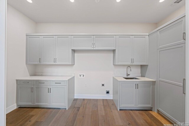 706 W Creek, Fredericksburg, TX 78624 - laundry area featuring hookup for an electric dryer, washer hookup, cabinets, sink, and light hardwood / wood-style flooring