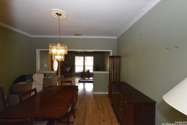 dining room with light wood-type flooring, an inviting chandelier, and crown molding