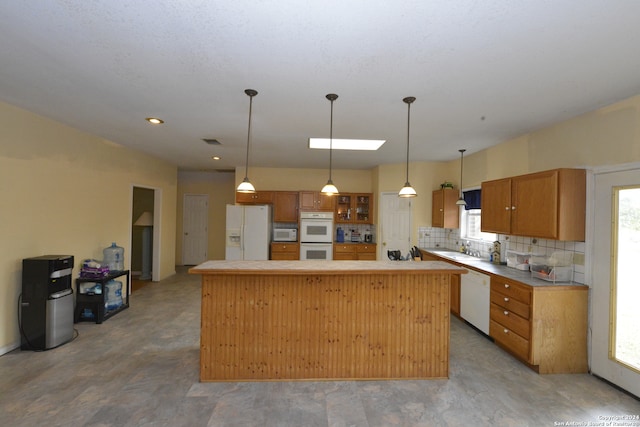 kitchen featuring pendant lighting, sink, decorative backsplash, white appliances, and a center island