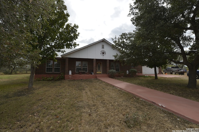 ranch-style house featuring a porch, a front yard, and a garage