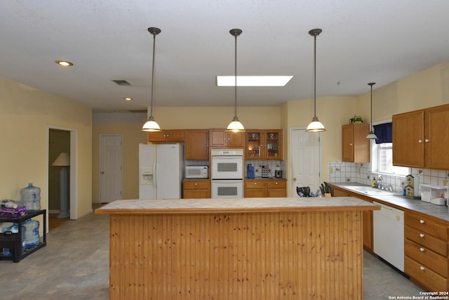 kitchen with decorative backsplash, sink, white appliances, and a kitchen island