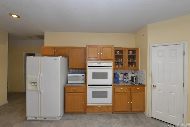 kitchen featuring tile counters, tasteful backsplash, and white appliances