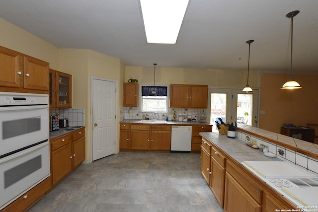 kitchen with backsplash, decorative light fixtures, tile counters, sink, and white appliances