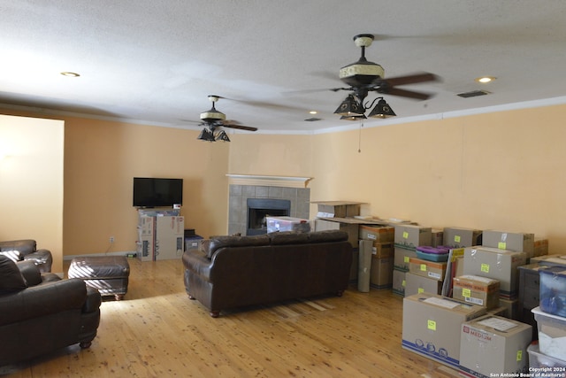 living room featuring a tiled fireplace, light hardwood / wood-style flooring, and ornamental molding