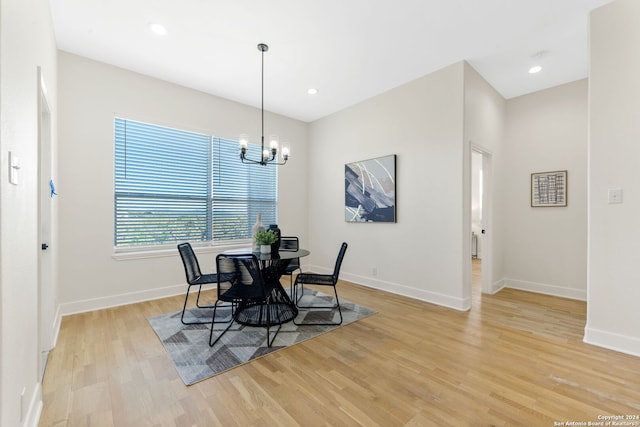 dining area with light hardwood / wood-style floors and a notable chandelier