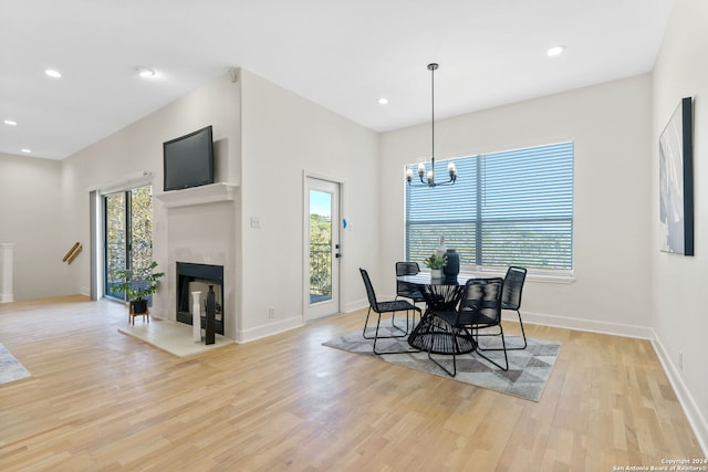 dining space featuring light wood-type flooring, an inviting chandelier, and a healthy amount of sunlight