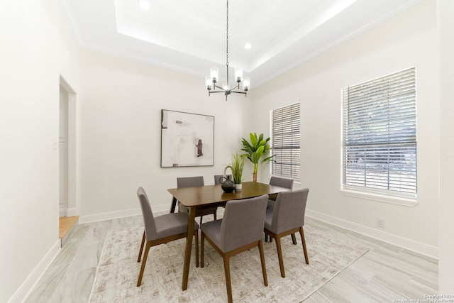 dining space featuring a tray ceiling, light hardwood / wood-style floors, and a notable chandelier