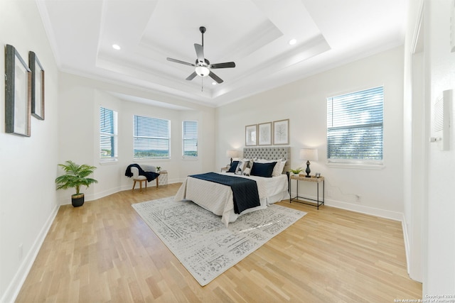 bedroom featuring ceiling fan, ornamental molding, a tray ceiling, and light hardwood / wood-style flooring