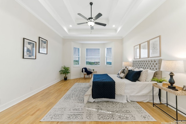 bedroom featuring a raised ceiling, ceiling fan, ornamental molding, and hardwood / wood-style flooring