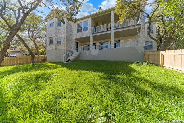 rear view of house with a yard and a balcony