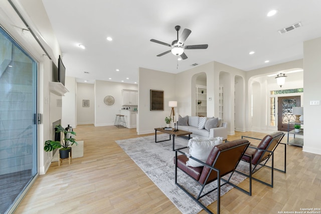 living room featuring ceiling fan, light hardwood / wood-style flooring, and built in features