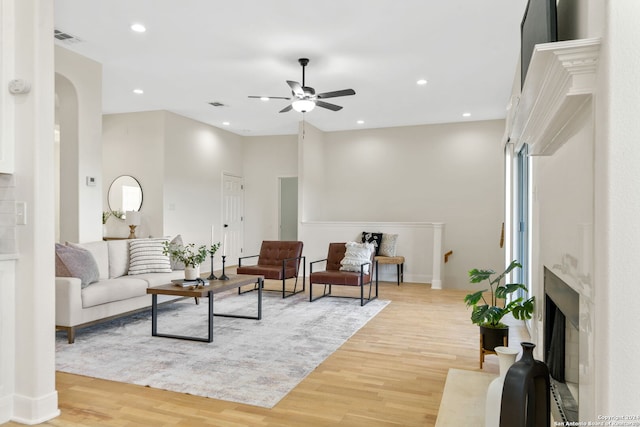 living room with ceiling fan, a premium fireplace, and light wood-type flooring