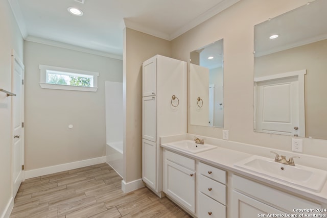 bathroom featuring a bath, hardwood / wood-style flooring, vanity, and crown molding