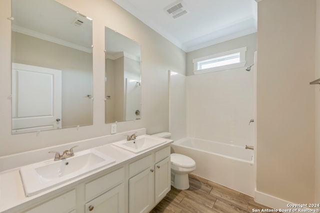 full bathroom with wood-type flooring, ornamental molding, vanity, shower / washtub combination, and toilet