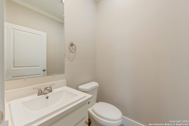 bathroom with toilet, vanity, and crown molding