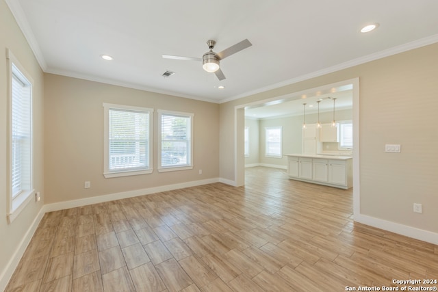 empty room with light hardwood / wood-style floors, plenty of natural light, and crown molding