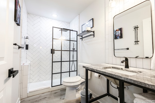 bathroom featuring toilet, a tile shower, hardwood / wood-style flooring, and sink