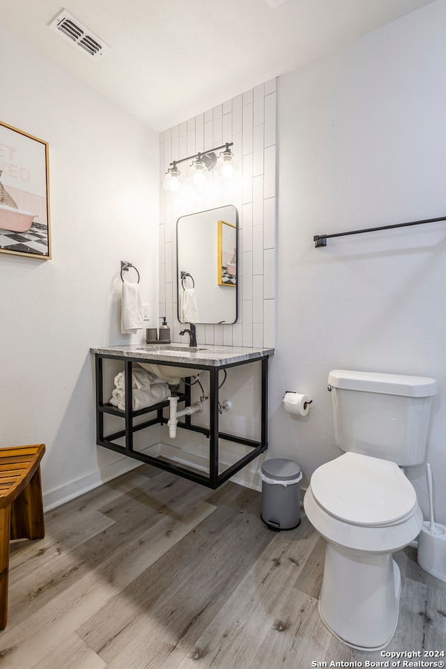 bathroom featuring wood-type flooring, toilet, and sink