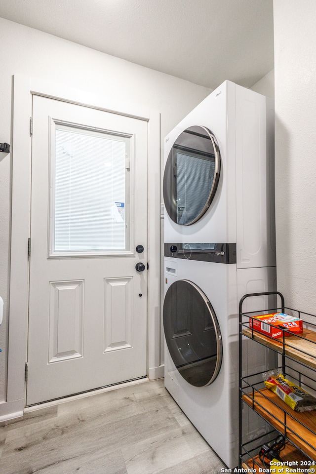 washroom with light hardwood / wood-style flooring and stacked washer and clothes dryer