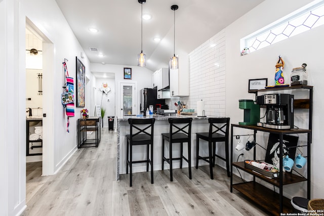 kitchen with kitchen peninsula, a breakfast bar area, light hardwood / wood-style flooring, white cabinets, and pendant lighting