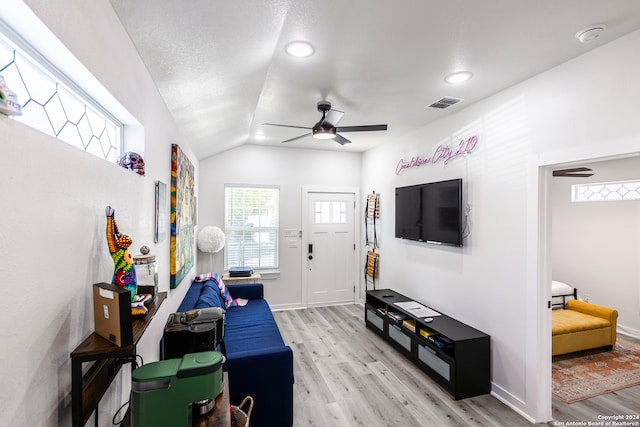 living room featuring ceiling fan, light wood-type flooring, and vaulted ceiling