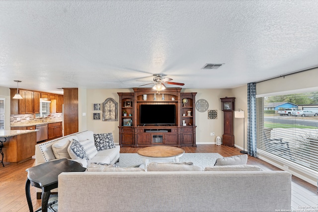 living room with a textured ceiling, light hardwood / wood-style floors, and ceiling fan