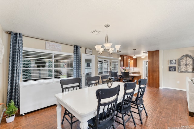 dining room with a chandelier, a textured ceiling, and hardwood / wood-style flooring