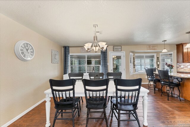 dining area featuring dark hardwood / wood-style flooring, a textured ceiling, and an inviting chandelier