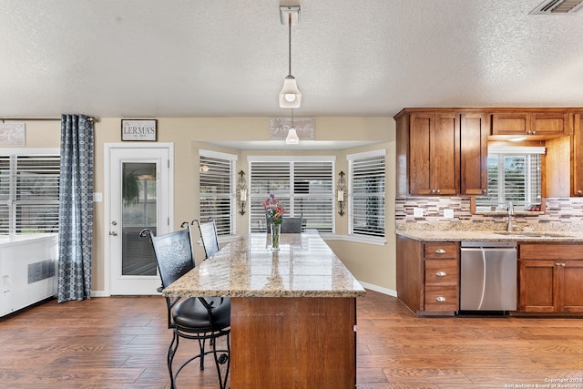 kitchen featuring hanging light fixtures, stainless steel dishwasher, dark hardwood / wood-style floors, and sink