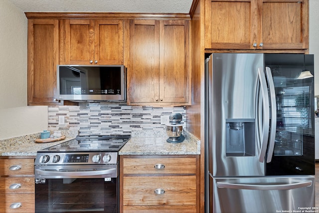 kitchen with decorative backsplash, appliances with stainless steel finishes, and light stone countertops