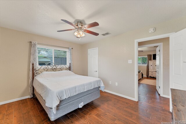 bedroom with dark hardwood / wood-style flooring, multiple windows, and ceiling fan