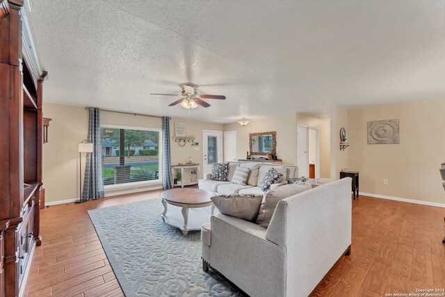 living room featuring a textured ceiling, light wood-type flooring, and ceiling fan