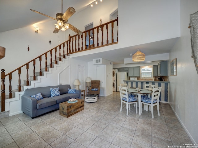 living room with a high ceiling, ceiling fan, and light tile patterned floors