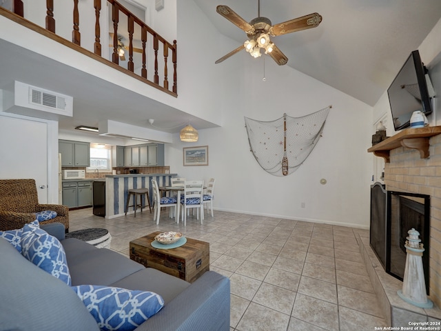 tiled living room with high vaulted ceiling, sink, ceiling fan, and a fireplace