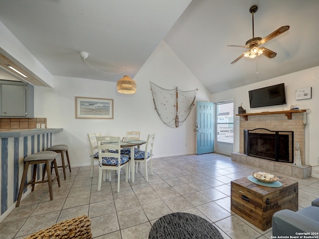 tiled dining area with a brick fireplace, ceiling fan, and vaulted ceiling