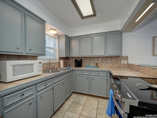 kitchen featuring tile countertops, gray cabinetry, and sink