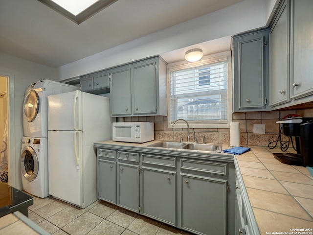 kitchen with tasteful backsplash, sink, white appliances, and stacked washer and clothes dryer