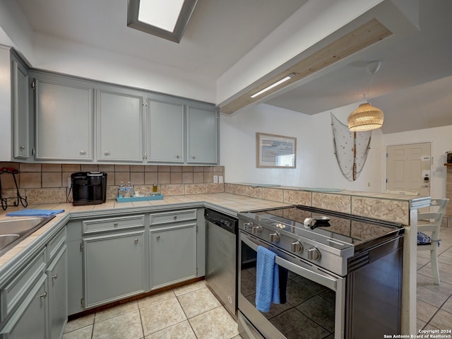 kitchen featuring kitchen peninsula, decorative backsplash, hanging light fixtures, gray cabinetry, and appliances with stainless steel finishes