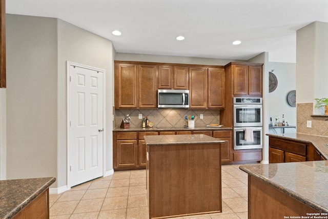 kitchen with stone counters, appliances with stainless steel finishes, decorative backsplash, and a center island