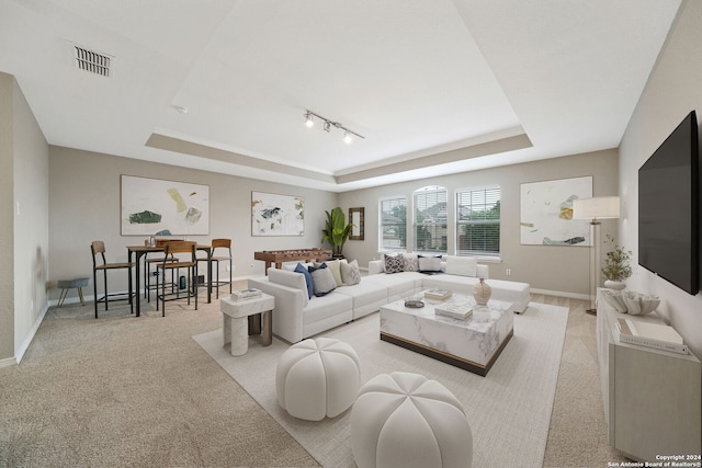 living room with rail lighting, light carpet, and a raised ceiling