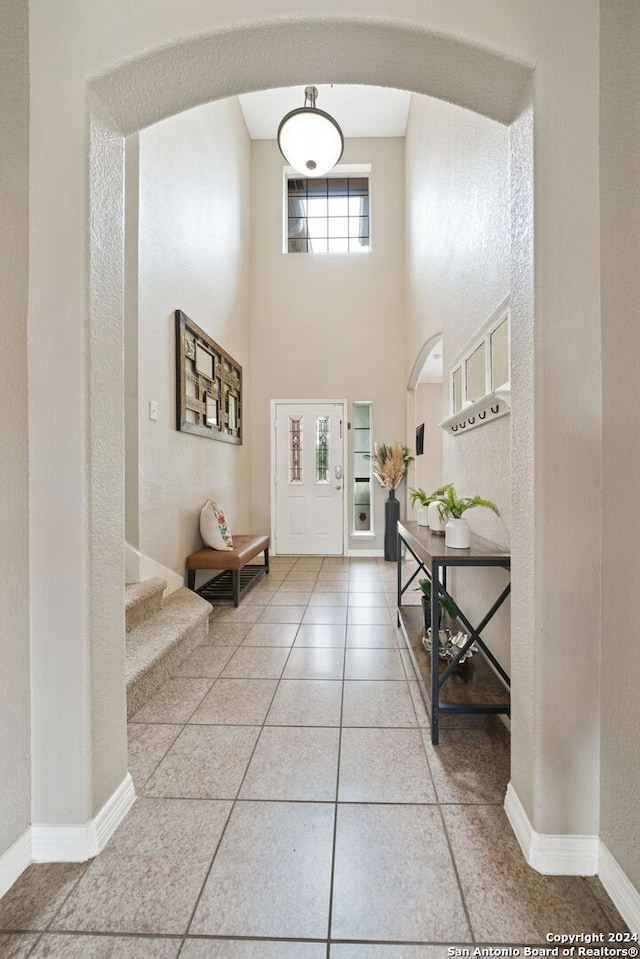 entrance foyer featuring a towering ceiling and tile patterned flooring