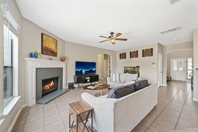 living room with a fireplace, ceiling fan, and light tile patterned floors