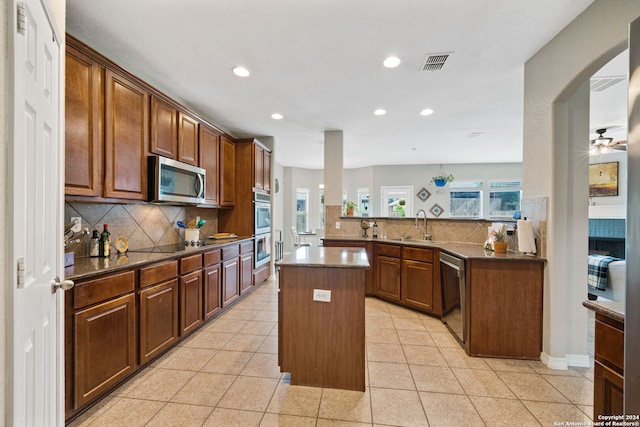 kitchen featuring stainless steel appliances, a healthy amount of sunlight, kitchen peninsula, and a center island