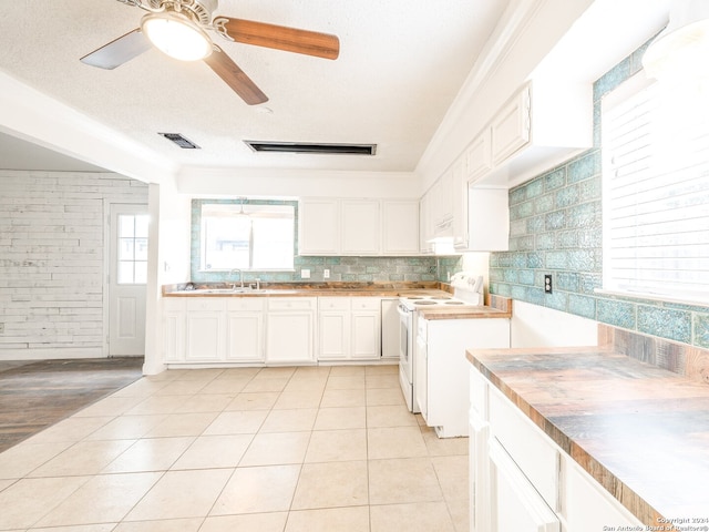 kitchen featuring light tile patterned floors, wood counters, tasteful backsplash, white electric stove, and white cabinets