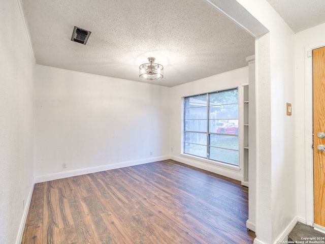 empty room with dark hardwood / wood-style flooring and a textured ceiling